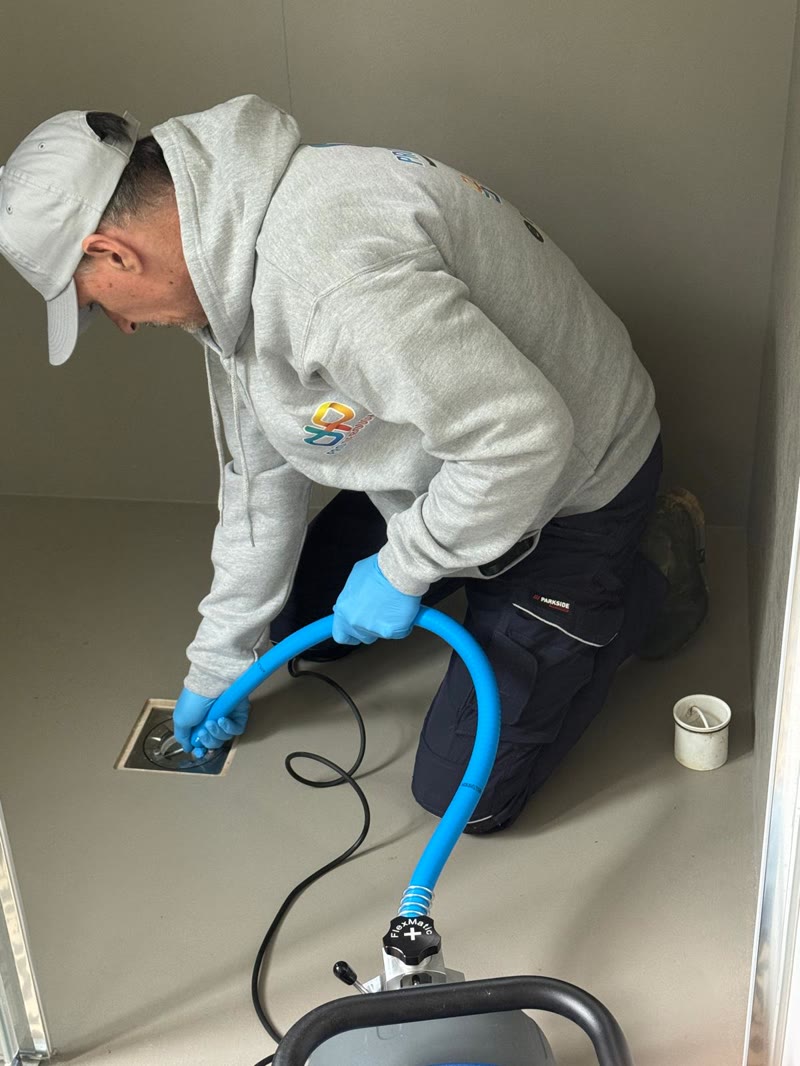 Technicien qui passe le furet électrique dans un siphon de douche.