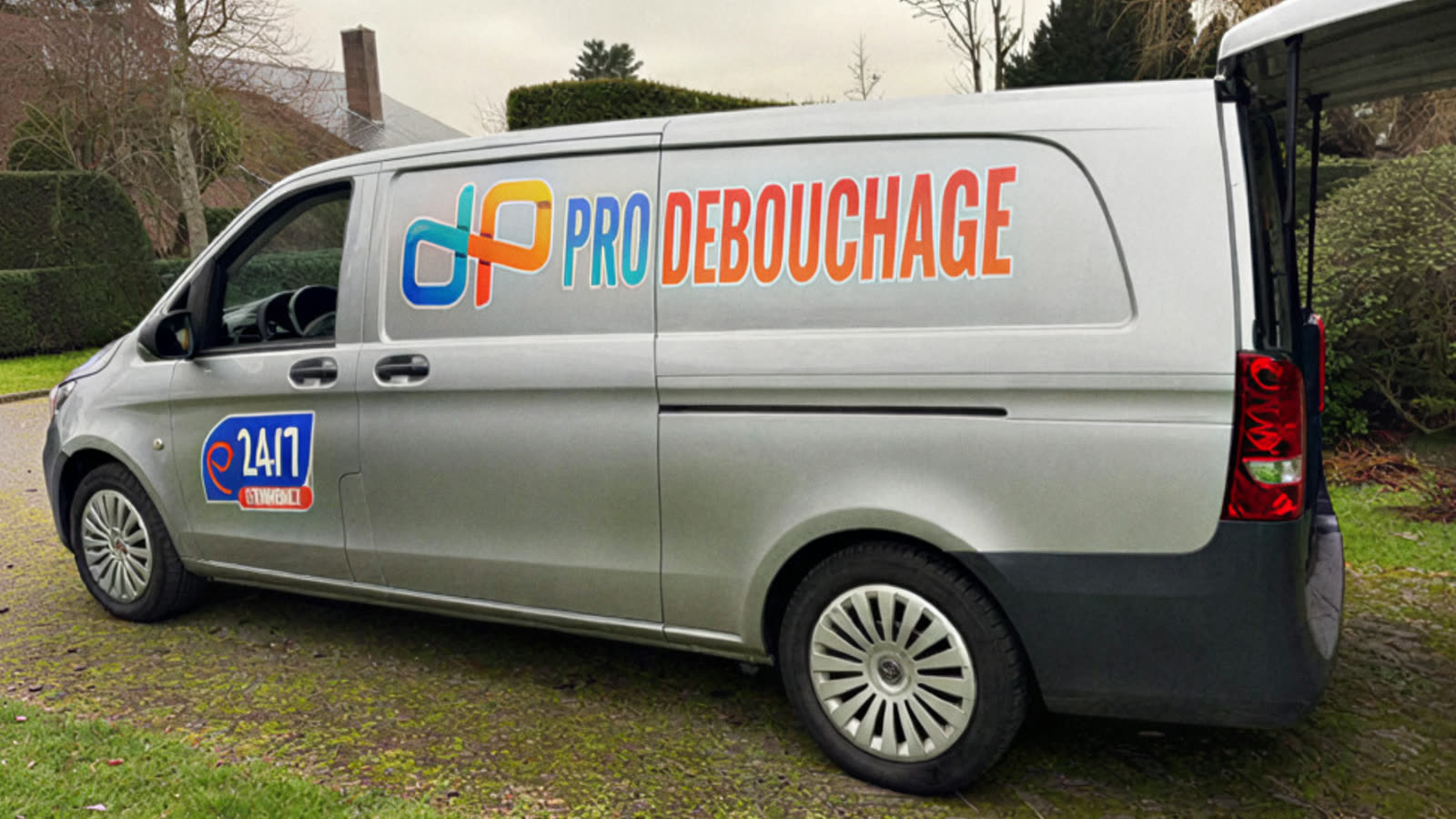 La camionnette dans un jardin, le logo Pro Débouchage sur le flanc.